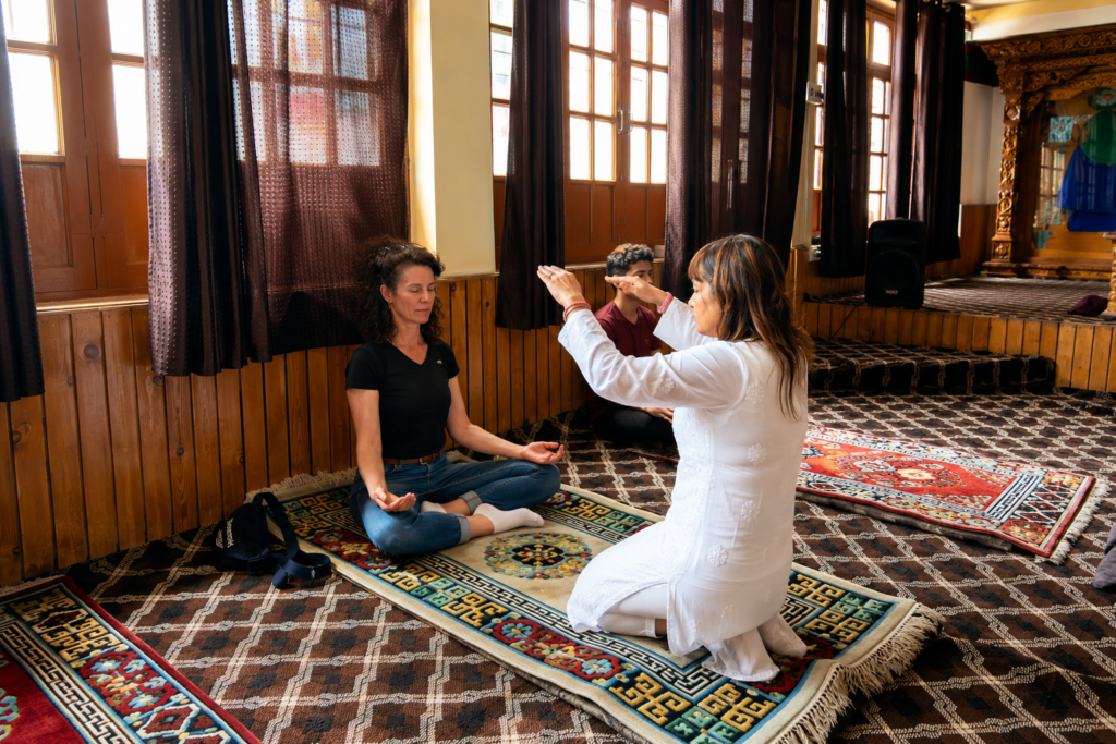 A Pranic healer conducting a one-to-one healing session with a participant inside a monastery in Ladakh.
